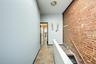 Hallway featuring baseboard heating, an upstairs landing, arched walkways, and brick wall