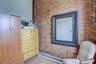 Unfurnished room featuring wood finished floors and brick wall