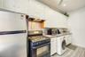 Kitchen featuring stainless steel microwave, extractor fan, washer / dryer, freestanding refrigerator, and black range with gas cooktop