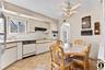 Kitchen with light countertops, white appliances, arched walkways, ceiling fan, and two tone cabinets