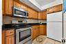 2nd Apartment Kitchen with stainless steel appliances, wood finish cabinetry, light tile patterned flooring, and decorative backsplash