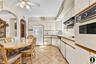 Kitchen featuring white appliances, light countertops, two tone cabinetry, a ceiling fan, and arched walkways