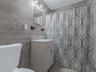 Bathroom with vanity, a shower with shower curtain, light tile patterned floors, and tile walls