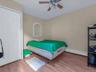 Bedroom with wood finished floors, a baseboard heating unit, and ceiling fan