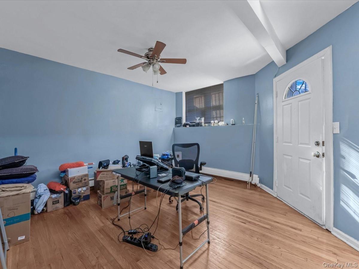 Office space featuring light wood-style flooring, ceiling fan, and beam ceiling