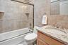 4th Bedroom - ensuite full bathroom with vanity, tile walls, shower / bath combination with glass door, and backsplash