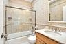 Third Oceanfront Bedroom en-suite bathroom. Full bath with tile walls, vanity, shower / bath combination with glass door, and tasteful backsplash