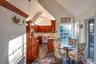 Dining area with high vaulted ceiling, ceiling fan, and stone tile floors