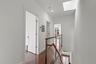 Hallway featuring an upstairs landing, a skylight, dark wood finished floors, and recessed lighting