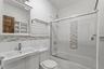 Full bath with vanity, combined bath / shower with glass door, tile walls, and wainscoting