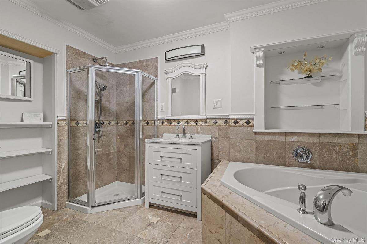 Full bath with a shower stall, a garden tub, vanity, crown molding, and tile walls