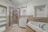 Full bath with a shower stall, a garden tub, vanity, crown molding, and tile walls