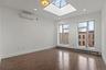 Unfurnished room featuring a skylight, dark wood-type flooring, a wall mounted AC, baseboard heating, and recessed lighting