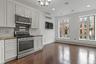 Kitchen featuring stainless steel appliances, decorative backsplash, white cabinetry, dark wood-type flooring, and baseboard heating