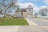View of front facade featuring stone siding, driveway, an attached garage, and roof with shingles