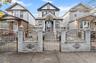 Victorian house with a gate, a fenced front yard, and brick siding