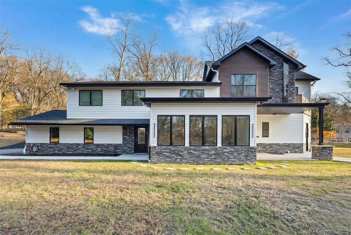 View of front of house featuring stone siding, a patio area, and a front yard