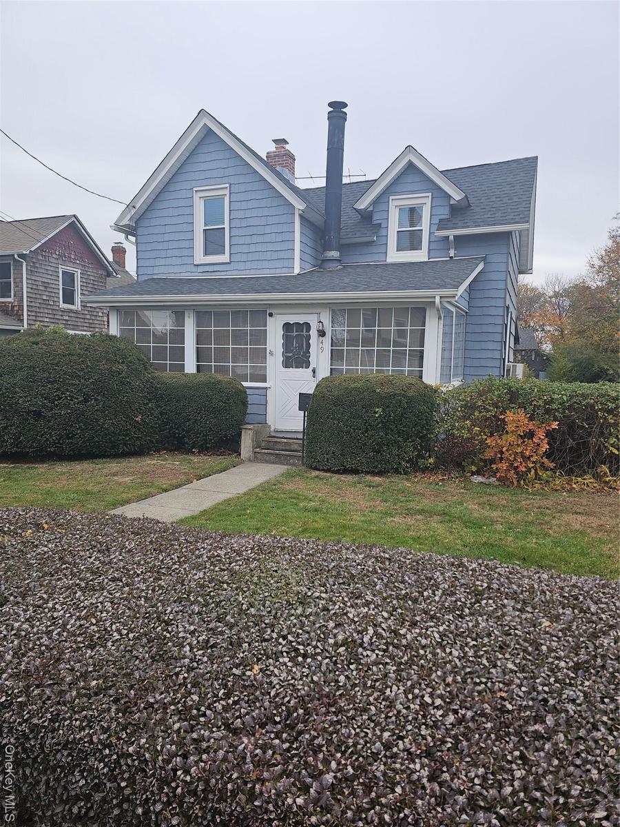 View of front of house with a chimney, a front yard, a shingled roof, and entry steps