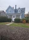View of front of house with a chimney, a front yard, a shingled roof, and entry steps