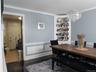 Dining area featuring dark wood-style flooring, a chandelier, a decorative wall, and wainscoting