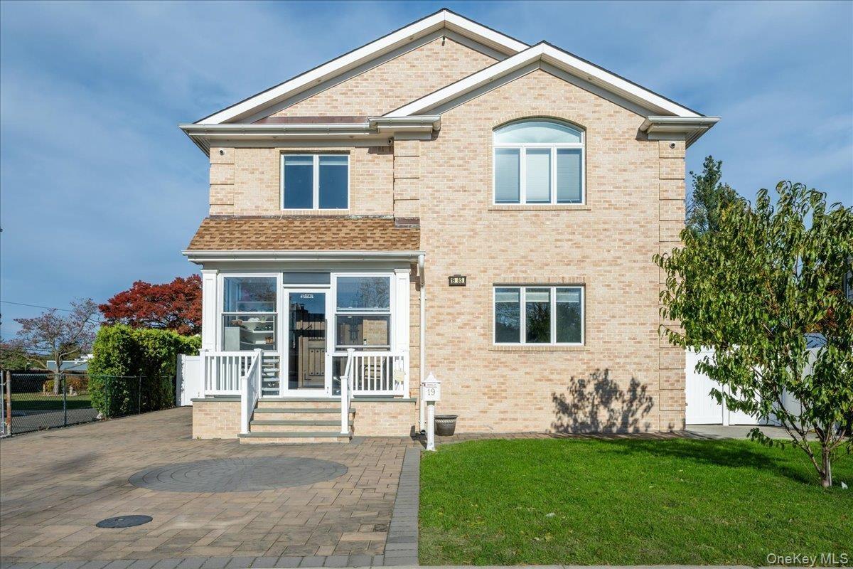 View of front of property featuring brick siding, a front yard, and a patio area