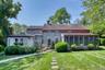 Rear view of property featuring a yard, a chimney, a sunroom, and roof with shingles