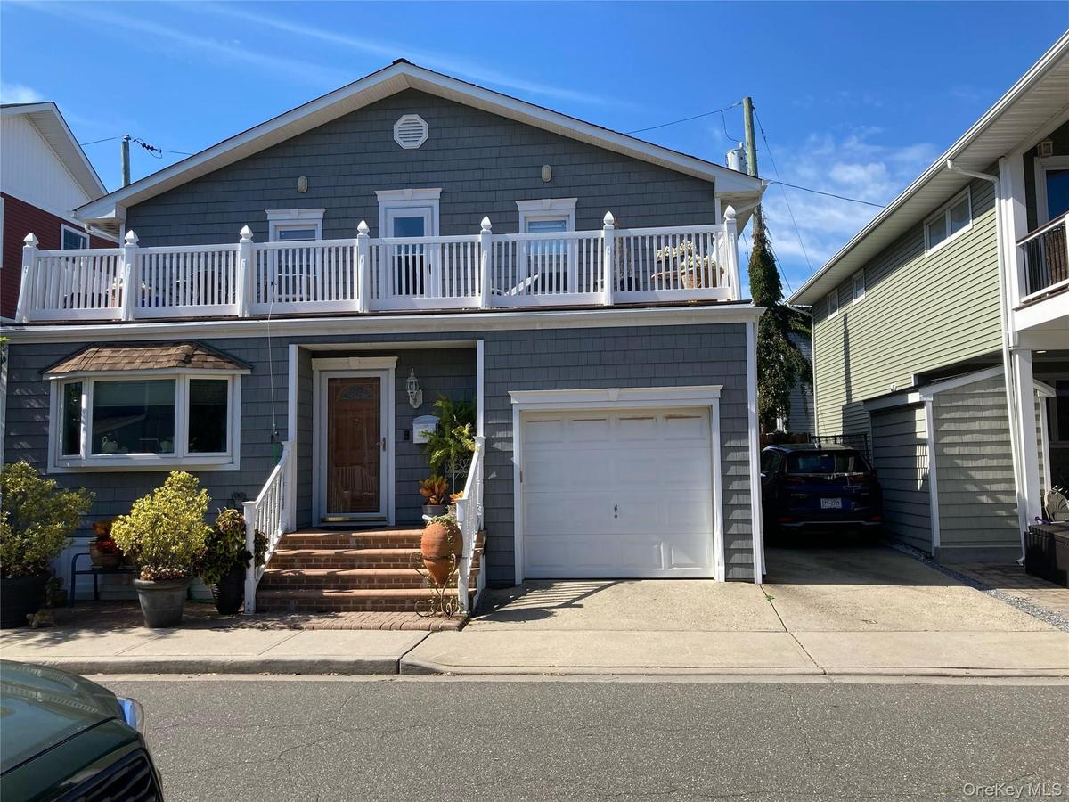 View of front of property with a garage, a balcony, and concrete driveway