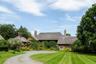 Tudor-style house with a chimney, a front lawn, driveway, and stone siding