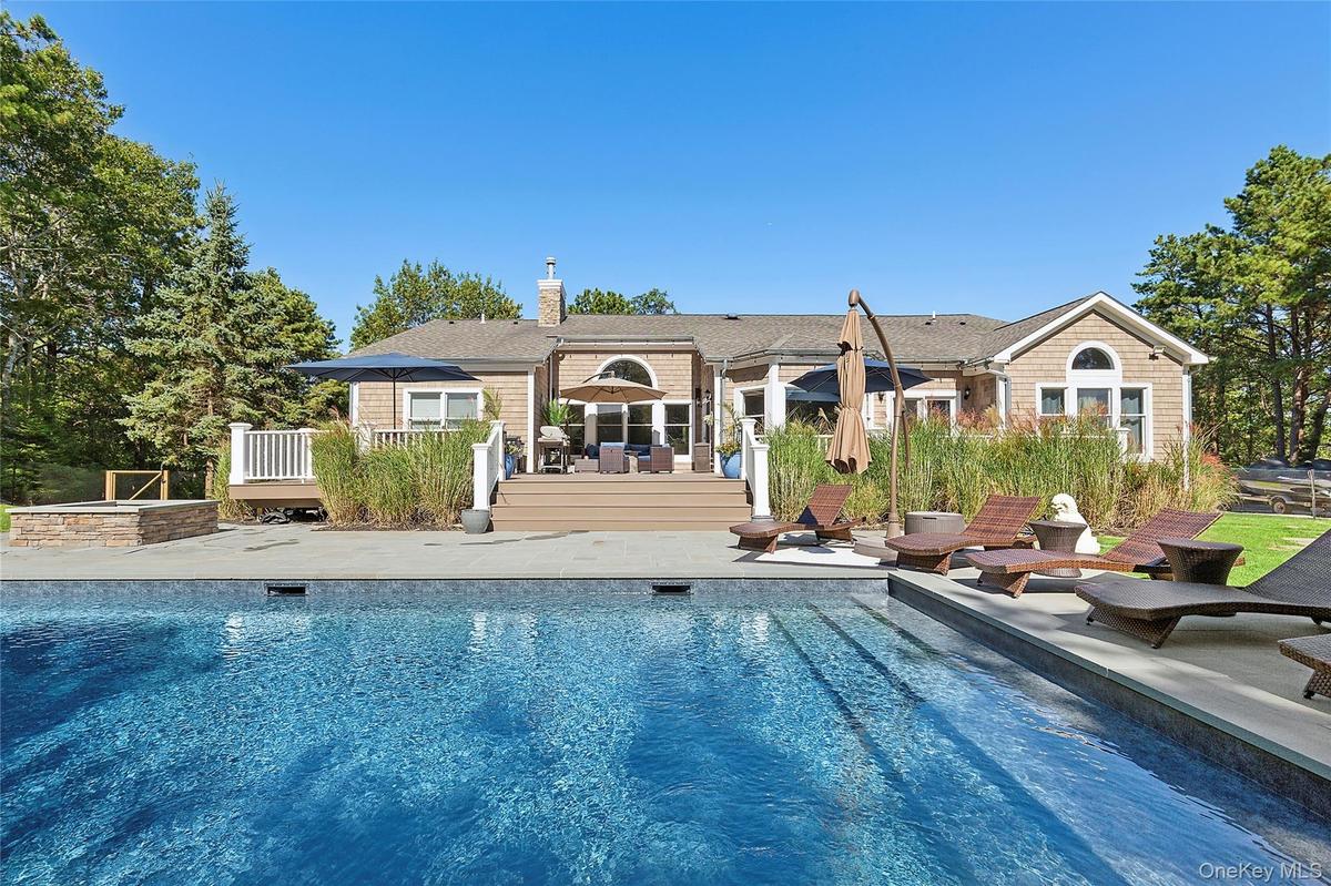 Rear view of property with a patio, a deck, roof with shingles, and an outdoor pool