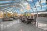 Sunroom / solarium featuring marble tiled flooring, high vaulted ceiling, a decorative wall, and a chandelier