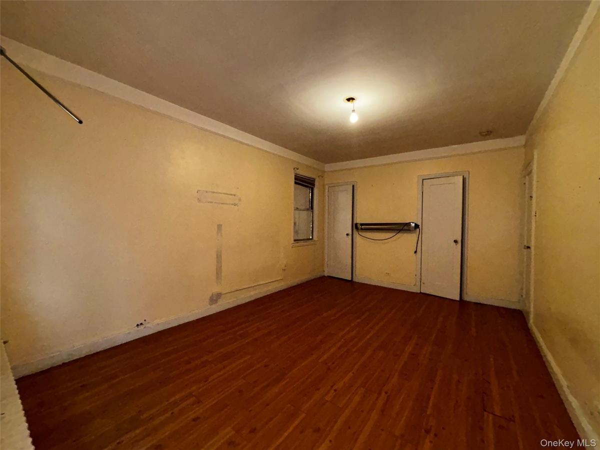 Spare room featuring dark wood-style flooring and ornamental molding