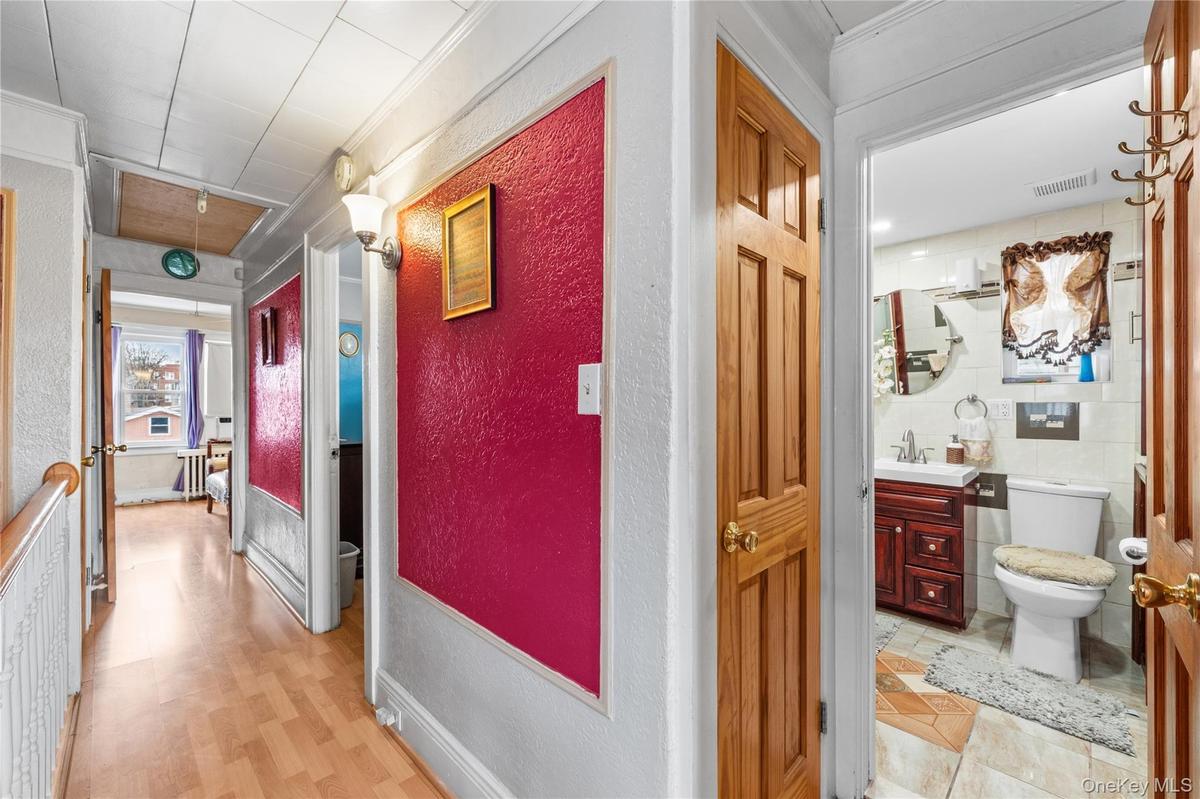 Corridor with attic access, a textured wall, and ornamental molding