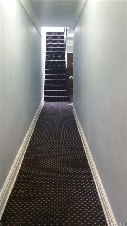 Hallway with carpet floors and baseboards