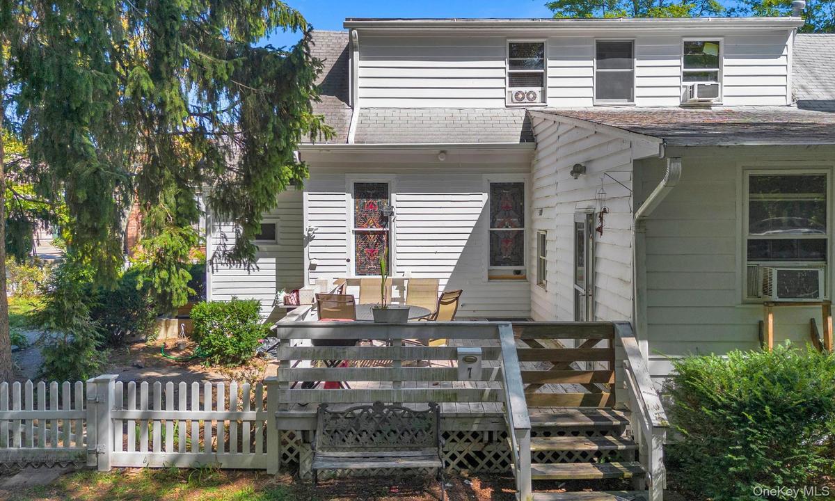 Rear view of house featuring a shingled roof, outdoor dining space, and a deck