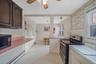 Kitchen featuring stainless steel electric range, a baseboard radiator, light countertops, light flooring, and black microwave