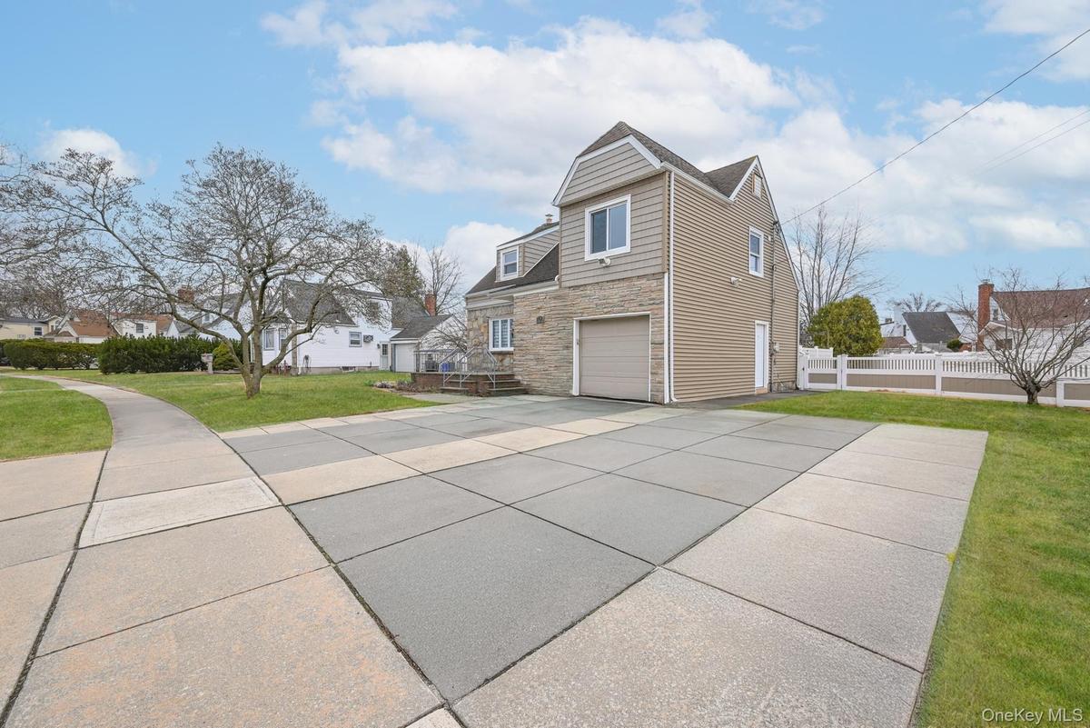 View of property exterior with stone siding, driveway, and an attached garage