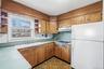 Kitchen with open shelves, freestanding refrigerator, light countertops, and brown cabinetry