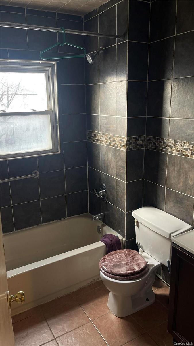 Bathroom featuring vanity, light tile patterned flooring, tile walls, and shower / washtub combination