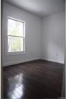 Spare room featuring dark wood-type flooring and baseboards