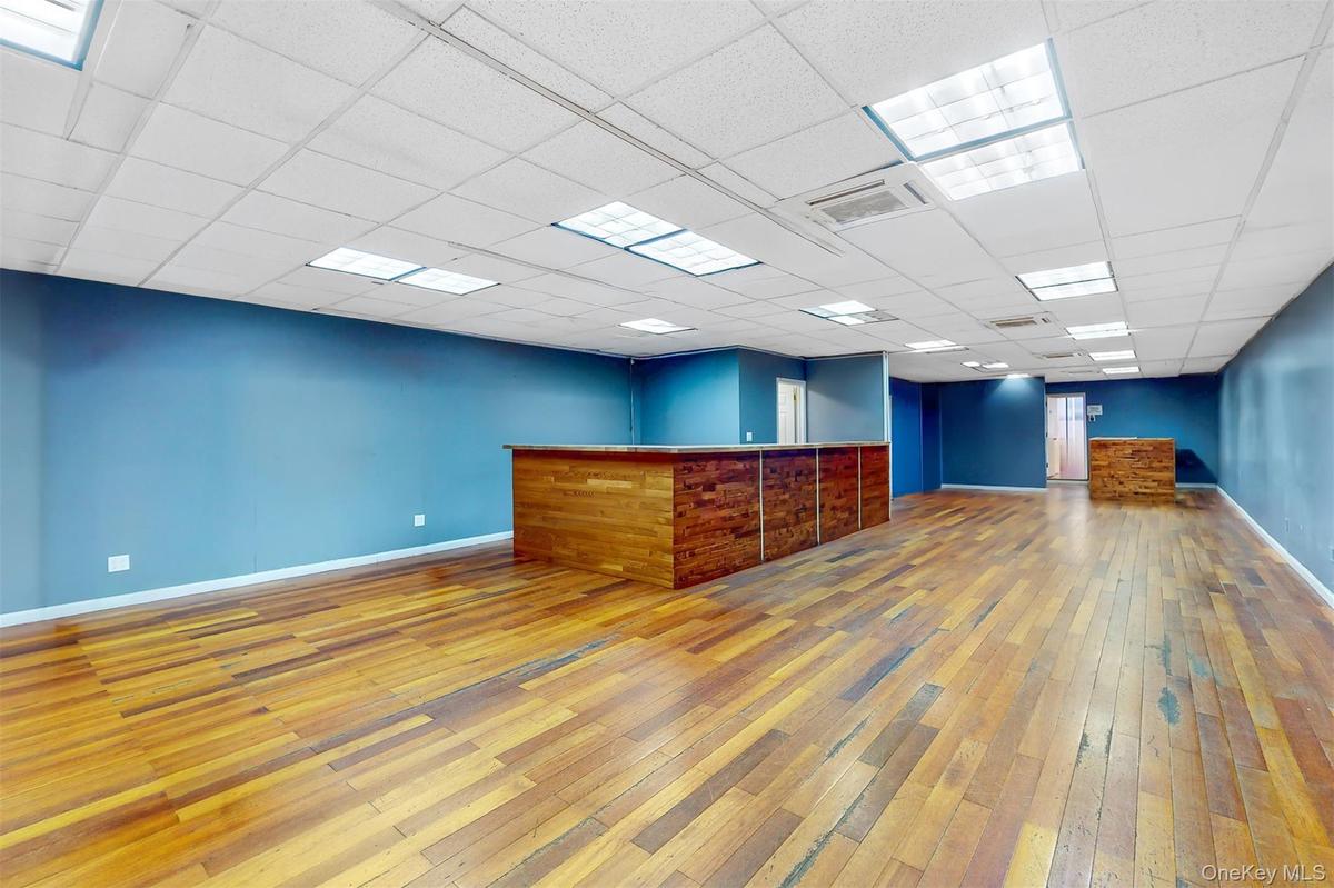 Empty room with light wood-style floors, a community bar, and a drop ceiling