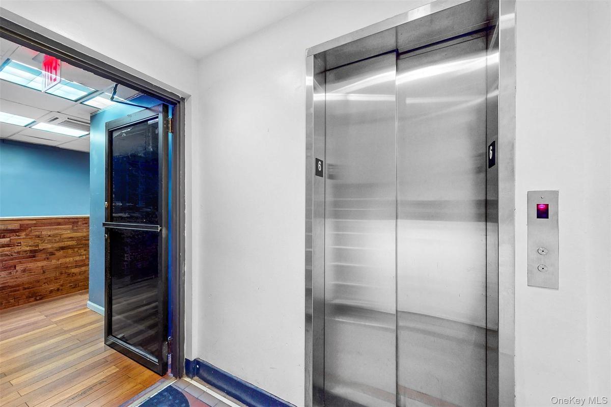 Bathroom featuring elevator, wood finished floors, wood walls, and a wainscoted wall