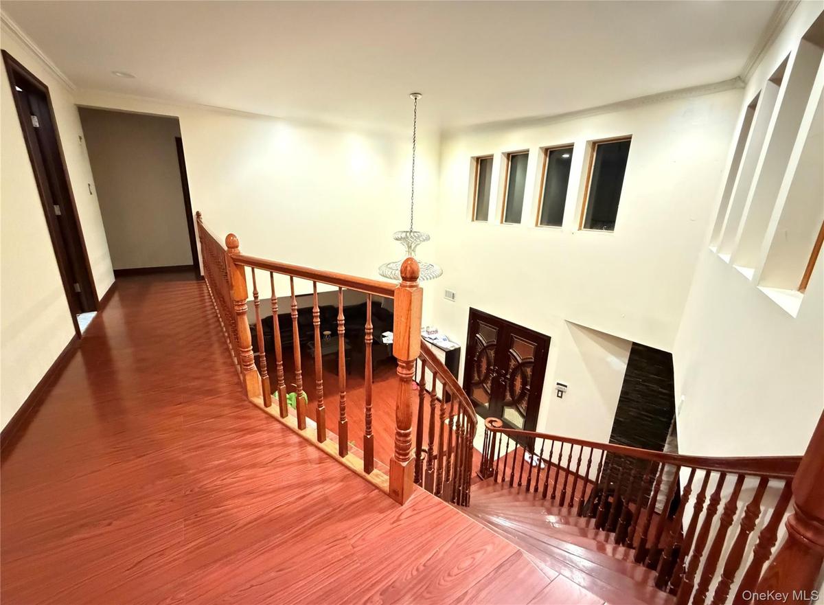 Staircase with wood finished floors and a chandelier