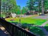 View of home's community with a swimming pool, uncovered parking, and view of wooded area