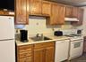 Kitchen featuring white appliances, light countertops, brown cabinets, and under cabinet range hood