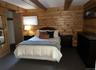 Carpeted bedroom with wooden walls and beam ceiling