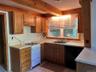 Kitchen featuring white range with gas cooktop, light countertops, light tile patterned floors, black dishwasher, and brown cabinets
