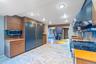 Kitchen featuring tasteful backsplash, appliances with stainless steel finishes, ventilation hood, brown cabinetry, and modern cabinets