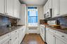 Kitchen featuring white range with gas stovetop, backsplash, radiator heating unit, stainless steel microwave, and granite floors