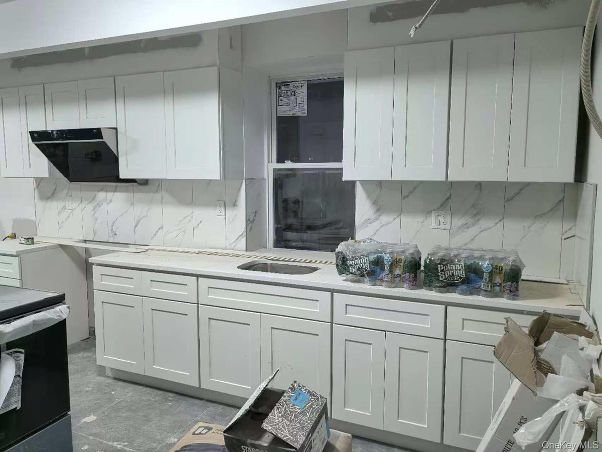 Kitchen featuring white cabinets, decorative backsplash, ventilation hood, and light stone counters