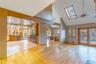 Unfurnished living room featuring light wood-type flooring, high vaulted ceiling, ceiling fan, and a skylight